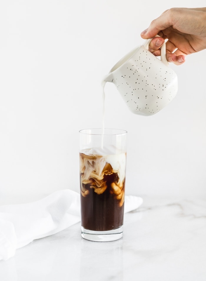 milk being poured into cold brew latte