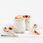 peach overnight oats in 2 glass jars with spoons beside them on a white and grey napkin.