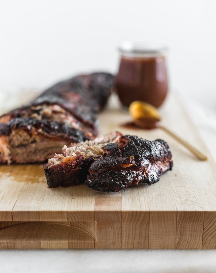 closeup of the end rib cut off a rack of BBQ ribs on a cutting board.