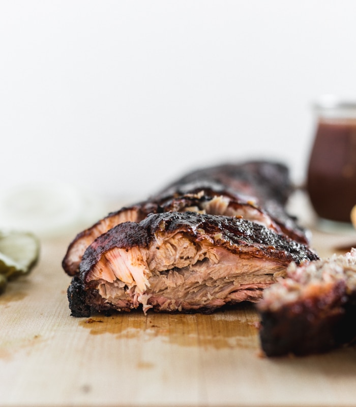 closeup of the cut side of a BBQ rib on a cutting board.