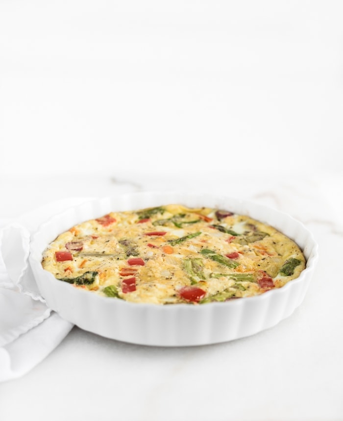 veggie frittata in a white round baking dish.