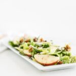 celery apple salad on a white rectangle serving dish.