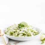 green apple jicama slaw with a lime wedge on top in a white bowl