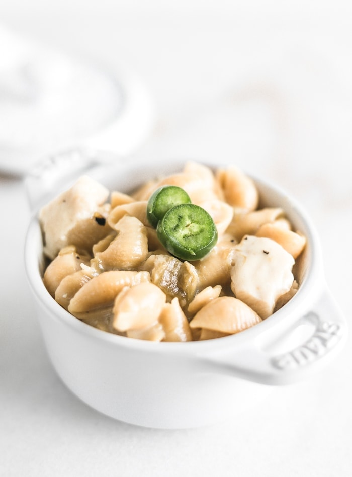 green chile chicken mac and cheese shells in a small white ramekin with jalapeno slices on top