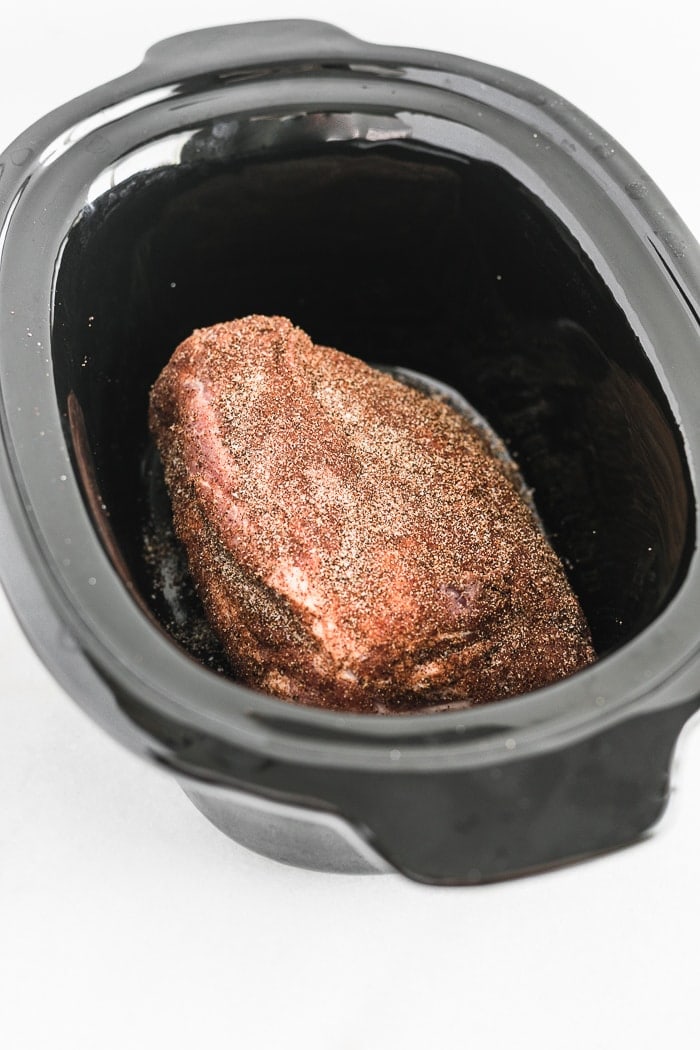 pork roast rubbed with spices in a slow cooker