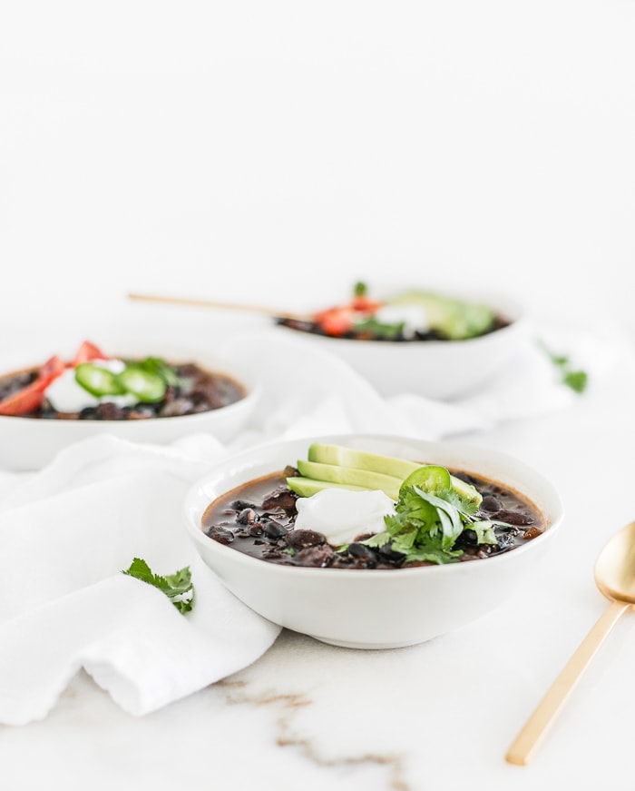 three white bowls of mexican black bean soup.