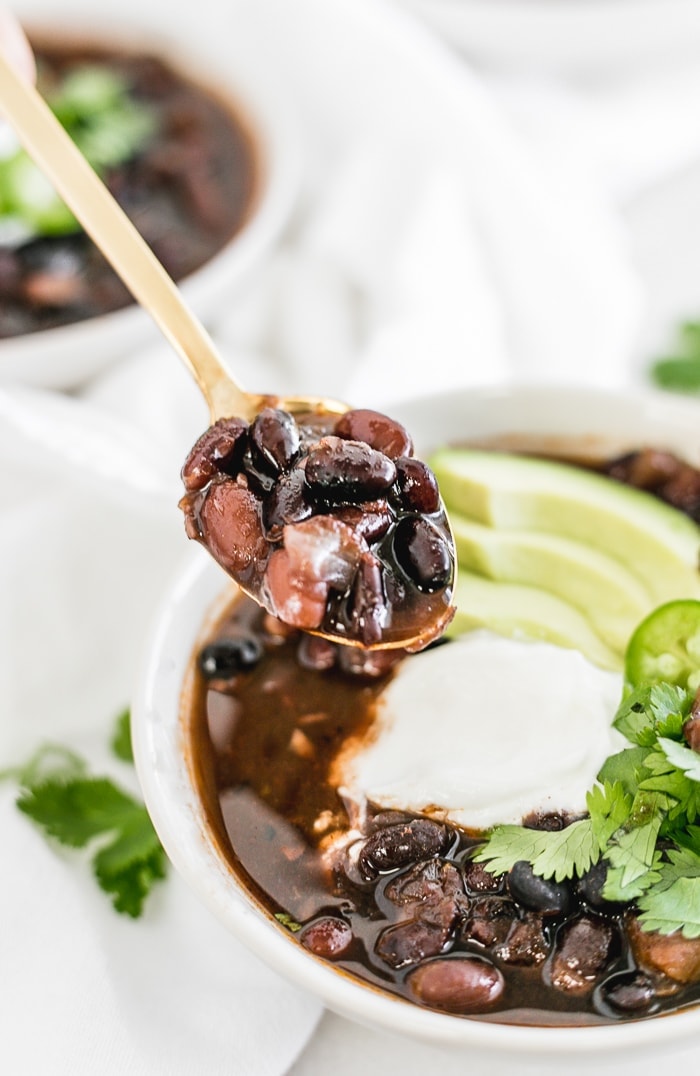 spoon lifting Mexican black bean soup from a bowl.