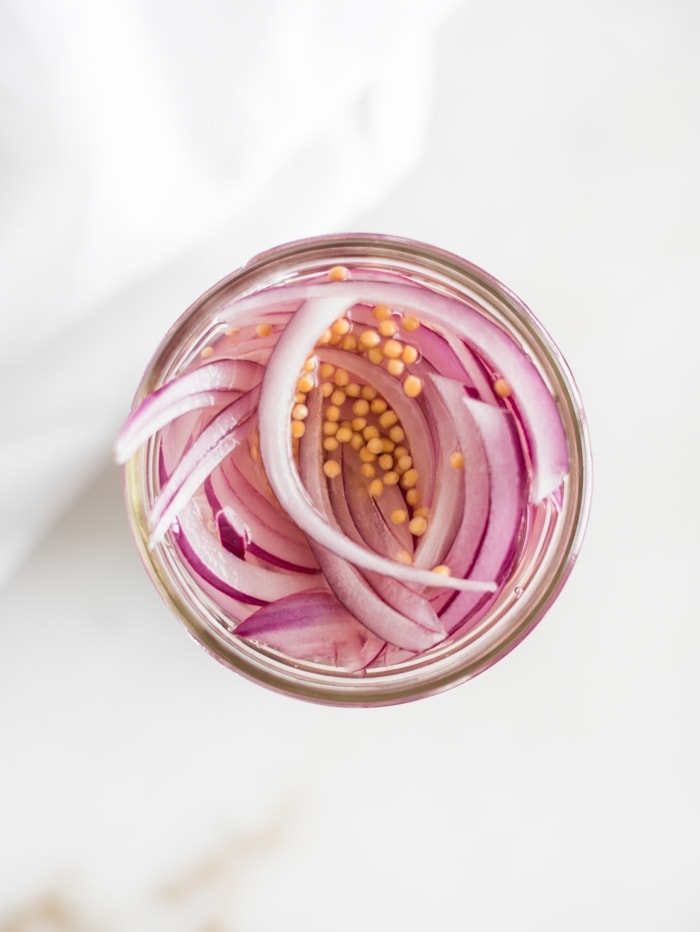 overhead shot of a jar of sliced red onions with pickling liquid in it.