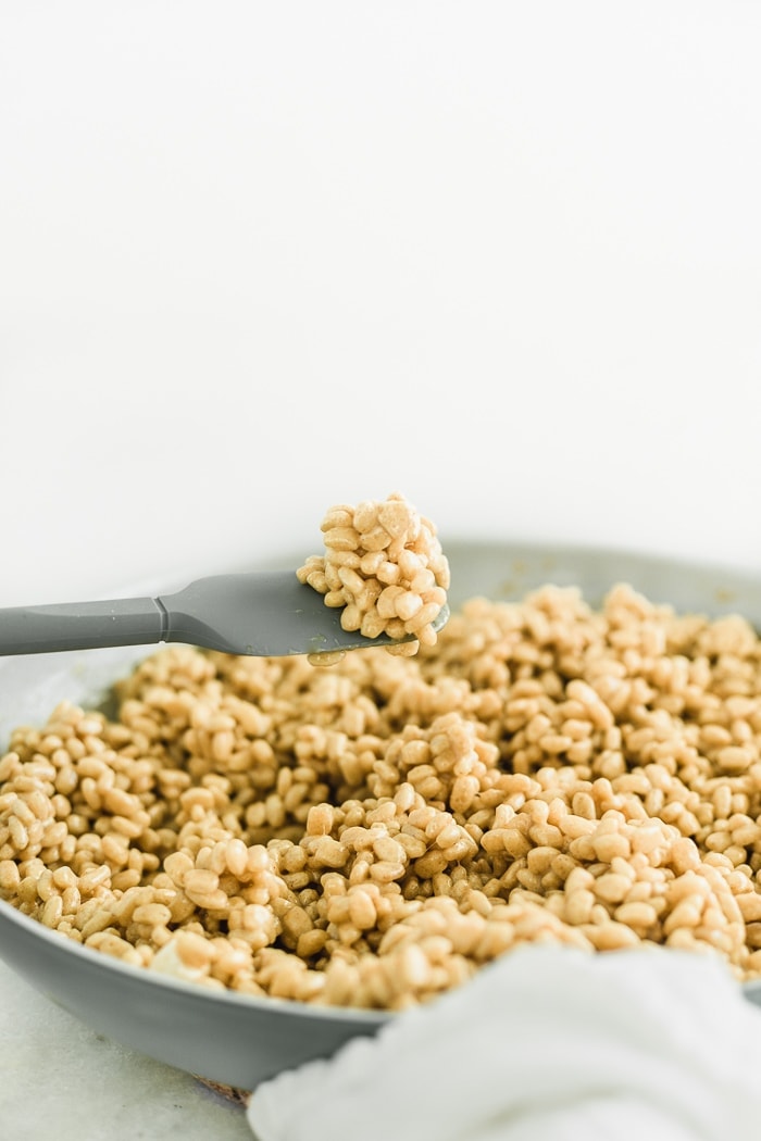 brown butter bourbon rice krispie treat mixture in a skillet with a spatula lifting some out of the pan.