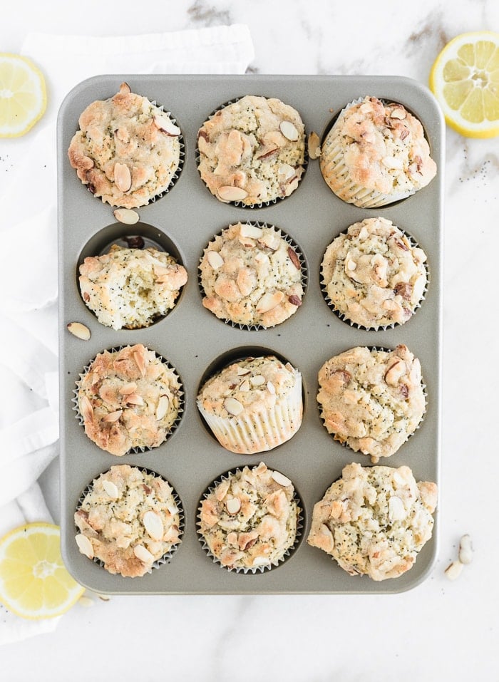 overhead view of lemon poppy seed muffins in a muffin tin surrounded by sliced lemons.