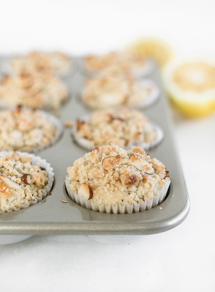 lemon poppyseed muffins with streusel topping in a muffin tin.