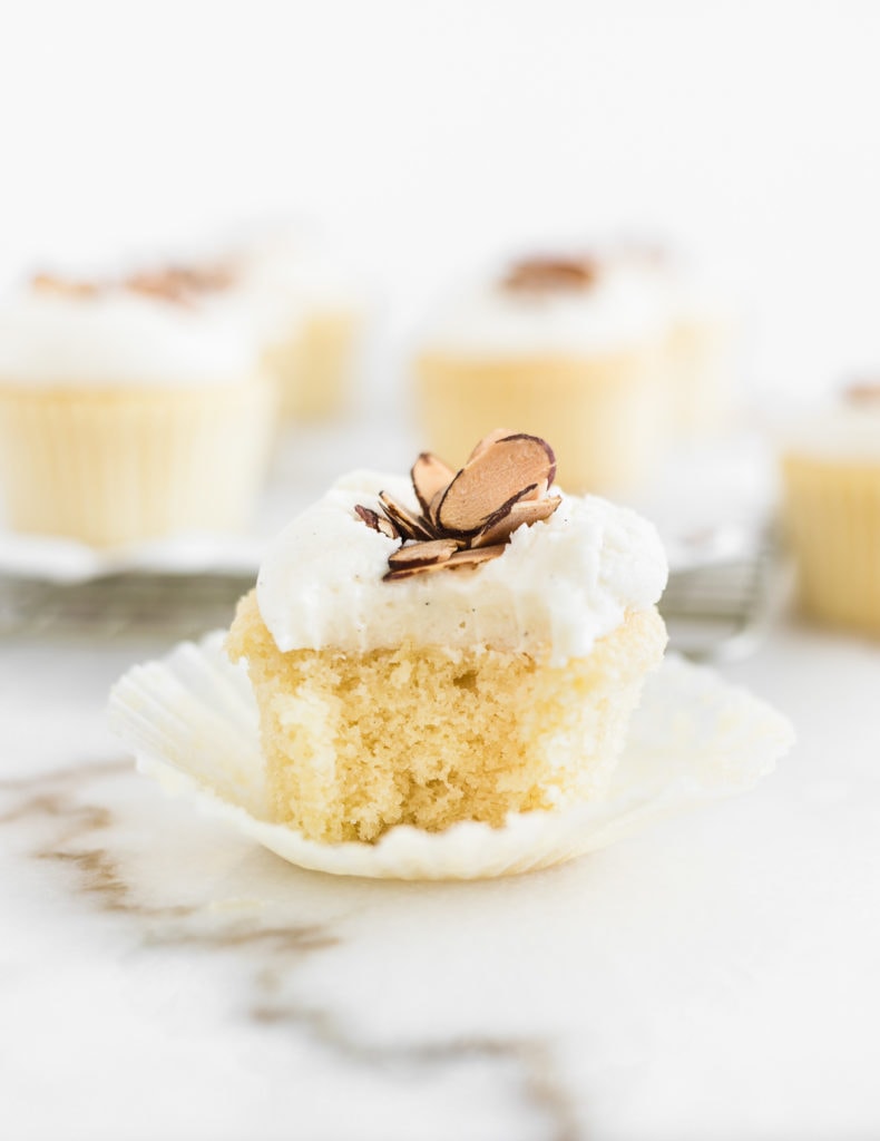 burnt almond cupcake on top of a cupcake liner with a bite taken out.