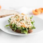 apricot chicken salad on top of arugula on a slice of bread.