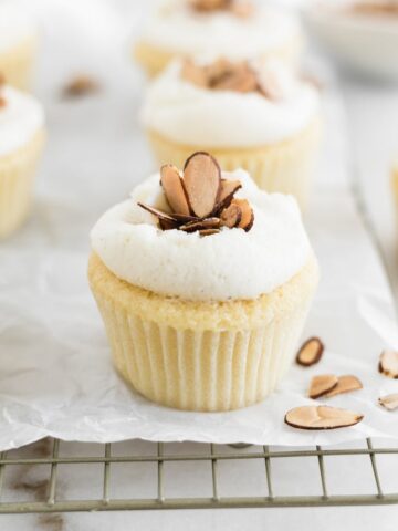 burnt almond cupcake on a cooling rack with more cupcakes in the background.