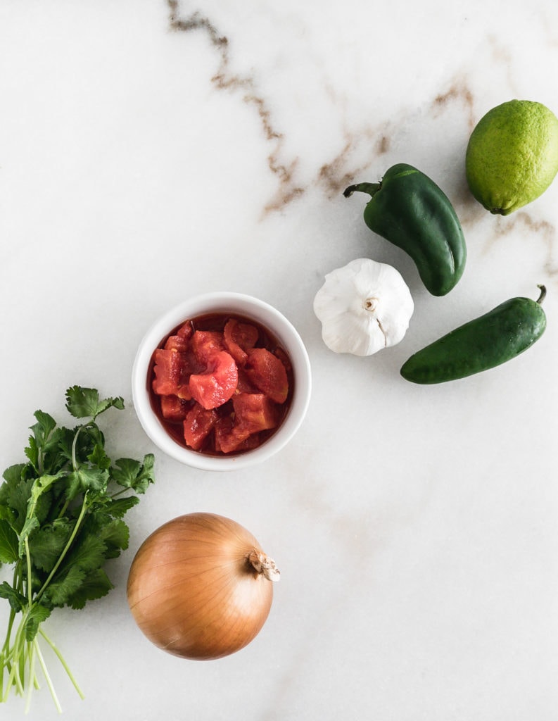 ingredients for fresh homemade salsa on a white marble background.