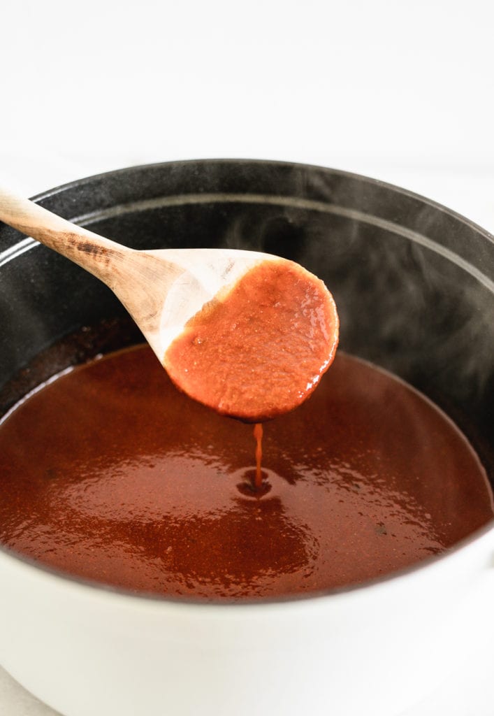 spoon dipping enchilada sauce out of a pot.