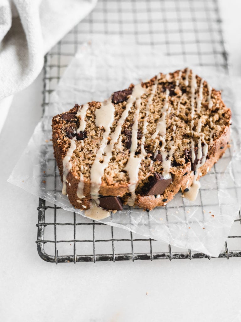 slice of tahini chocolate chip banana bread on a metal cooling rack drizzled with tahini.