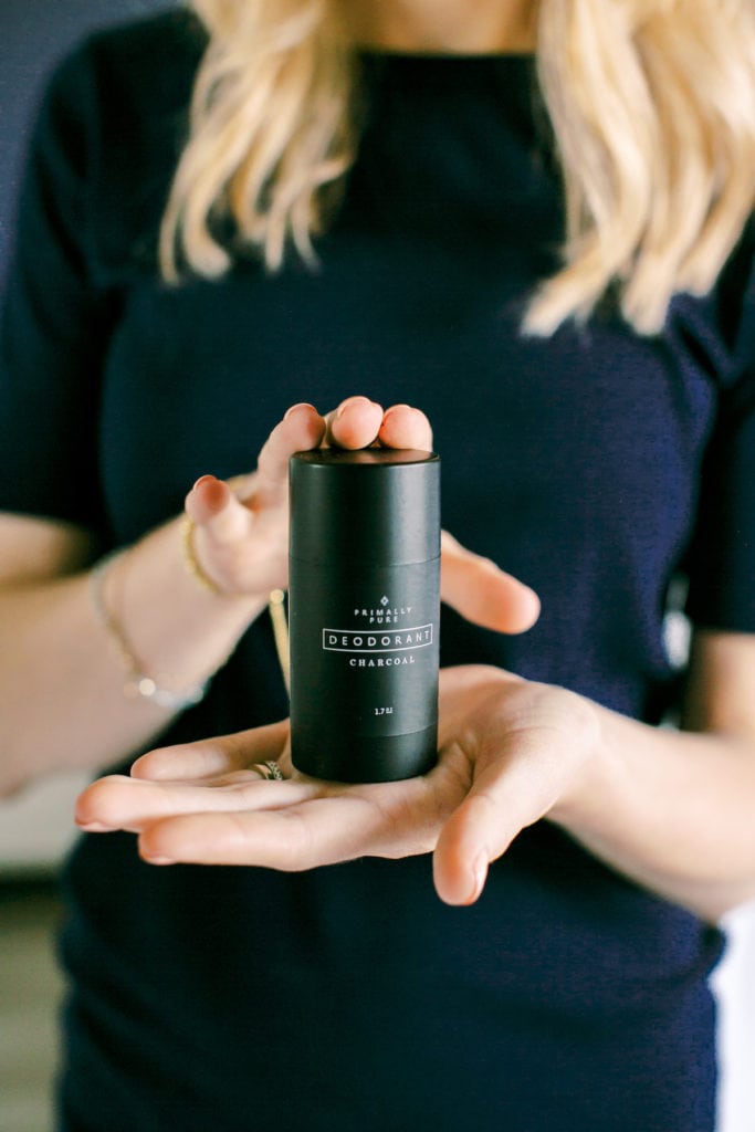 closeup of a woman's hands holding a black bar of deodorant.