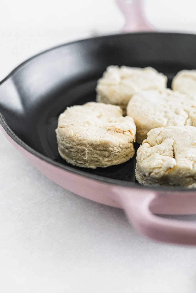 unbaked sourdough biscuits in a pink cast iron skillet.