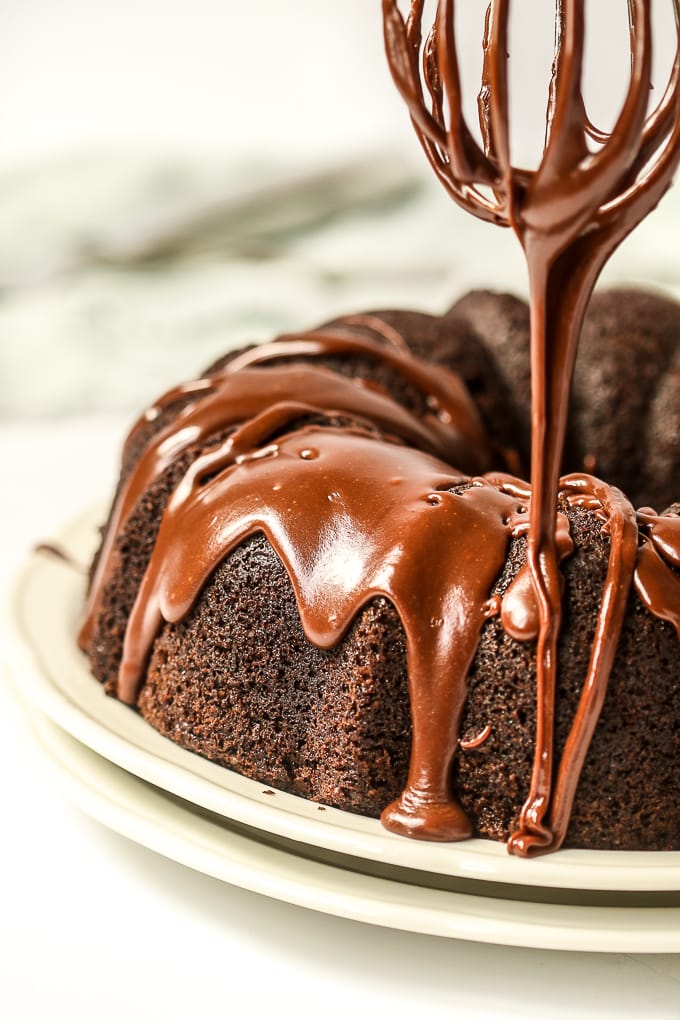 closeup of sourdough chocolate bundt cake with icing being drizzled over it.