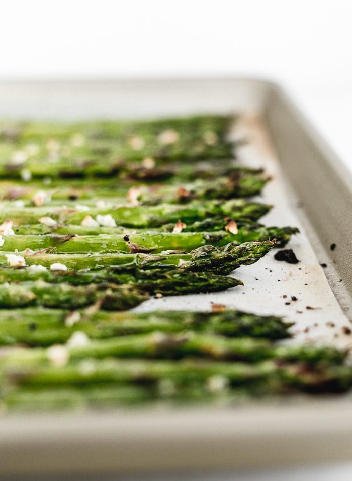 closeup of broiled asparagus on a baking sheet.