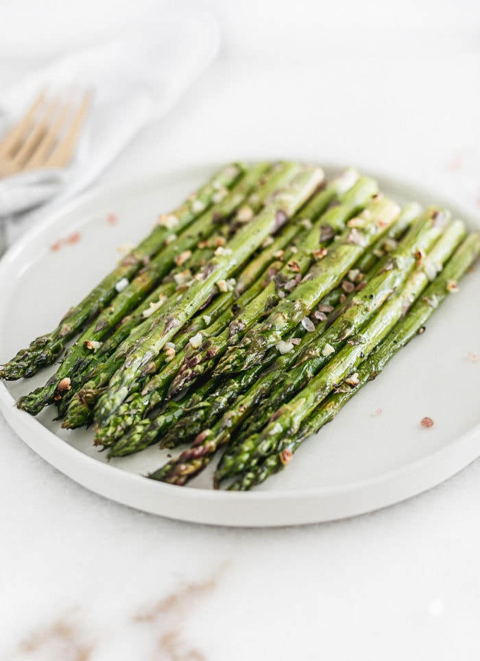 broiled asparagus on a white plate.