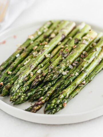broiled asparagus on a white plate.