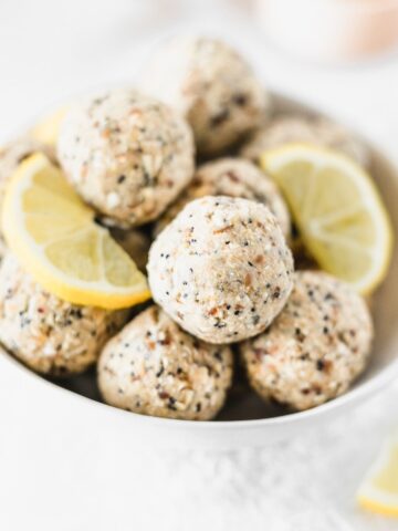 lemon poppy seed balls in a white bowl with lemon slices.