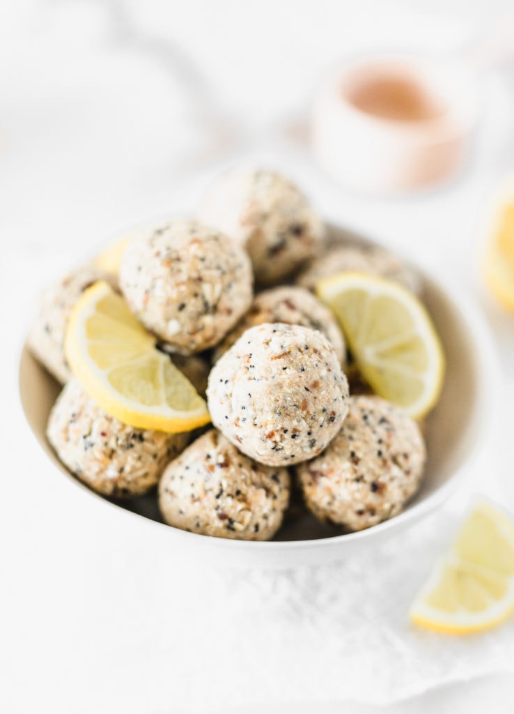 lemon poppy seed balls in a white bowl with lemon slices.