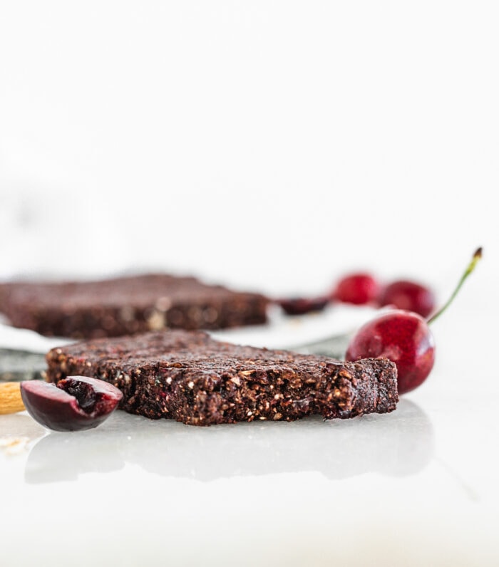 no bake dark chocolate cherry bar with a bite taken out on a white background.