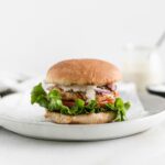 shrimp caeser burger on a wheat bun on a grey plate.