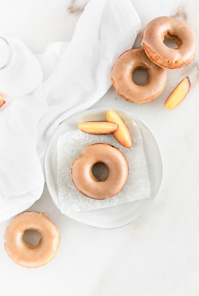 overhead view of baked peach donuts with brown sugar glaze with sliced peaches.