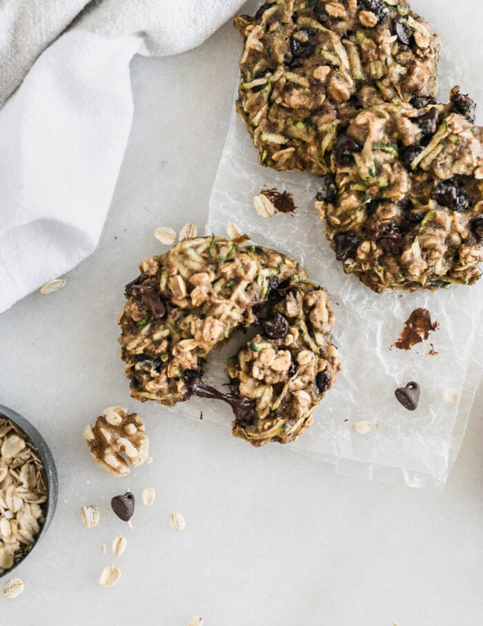 overhead view of zucchini breakfast cookies with one cookie being pulled apart. 