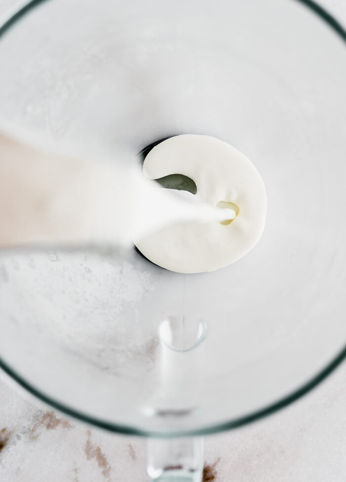 overhead view of cream being poured into a glass bowl.