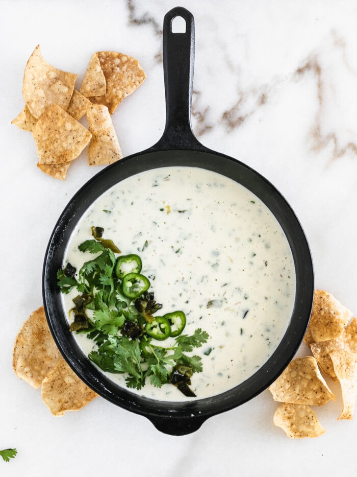 overhead view of a cast iron skillet with skillet queso blanco surrounded by tortilla chips.