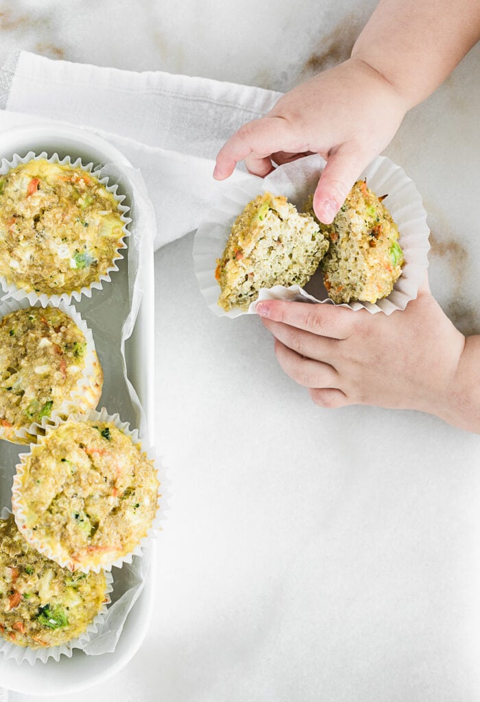 toddler hand grabbing a quinoa muffin cut in half.