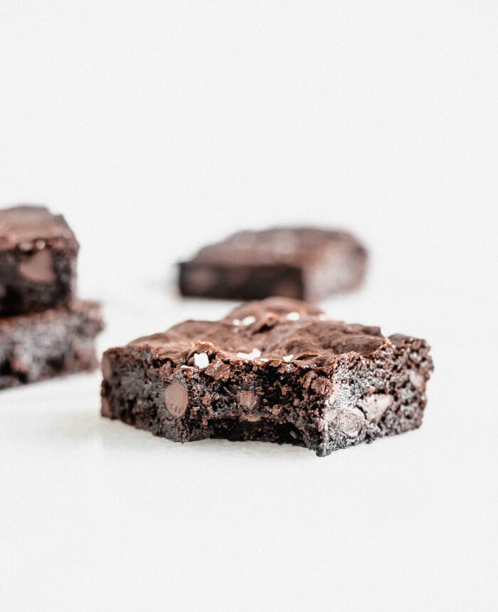 olive oil brownie with a bite taken out with brownies in the background.