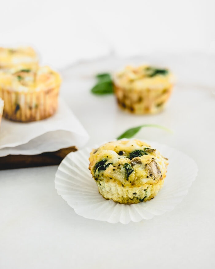 spinach egg muffin on top of a paper muffin liner.