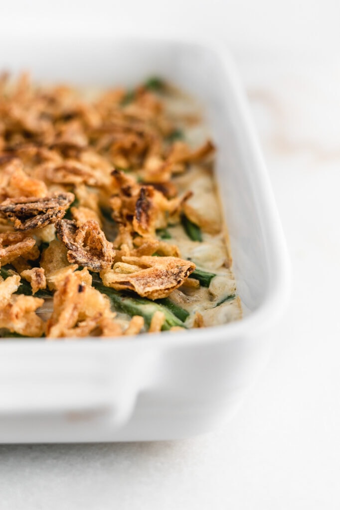 closeup of green bean casserole topped with crispy onions in a white baking dish.
