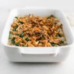 green bean casserole topped with crispy onions in a white baking dish.