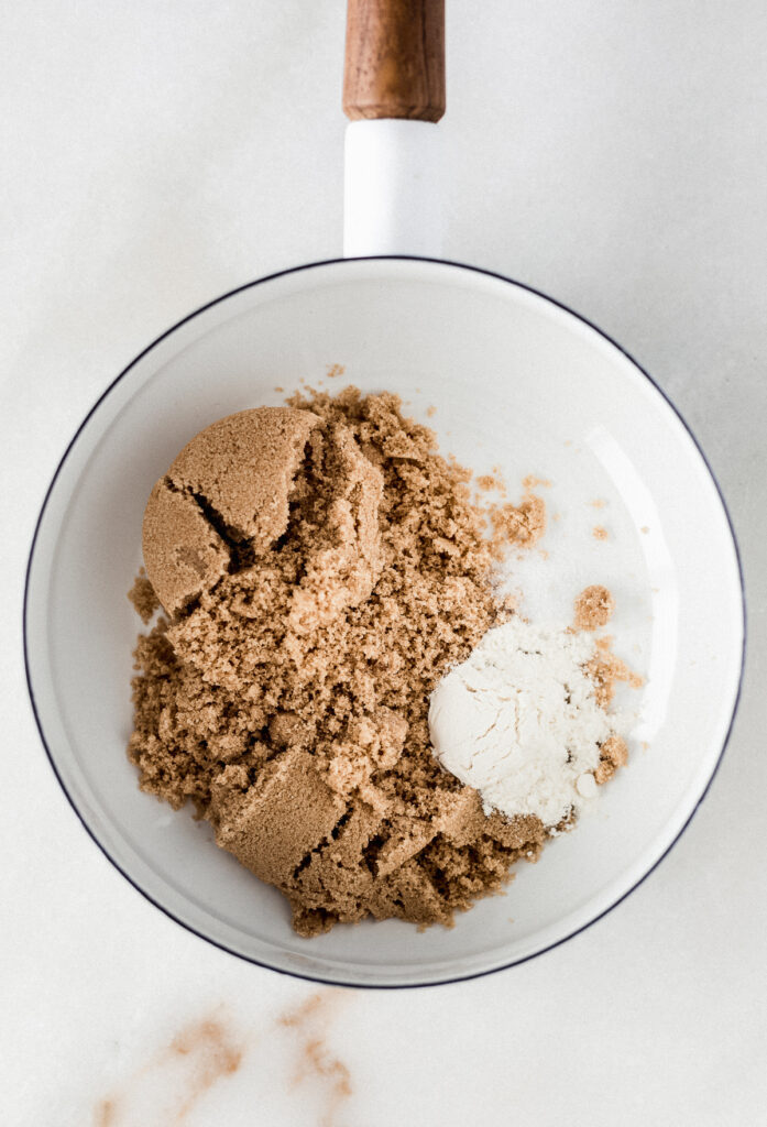 overhead view of brown sugar, flour and salt in a white saucepan.