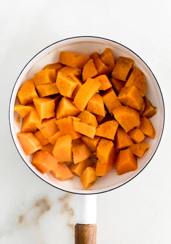 boiled, drained sweet potato cubes in a white saucepan.