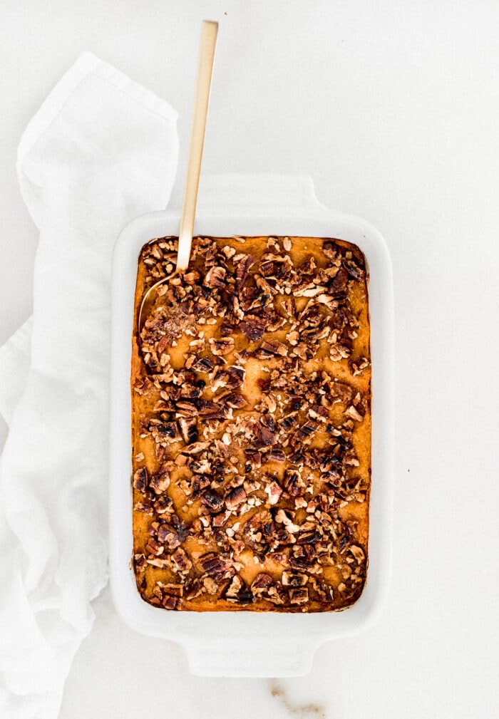 overhead view of sweet potato casserole in a white dish with a gold spoon in it.