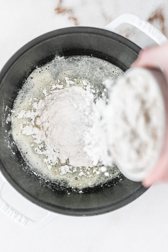overhead view of flour being sprinkled into the bottom of a pot.