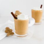 gingerbread smoothie in a glass topped with whipped cream and a gingerbread man.