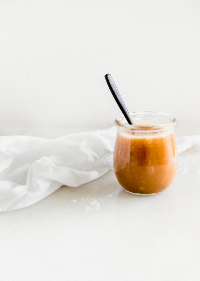salted miso caramel in a glass jar with a black spoon in it.