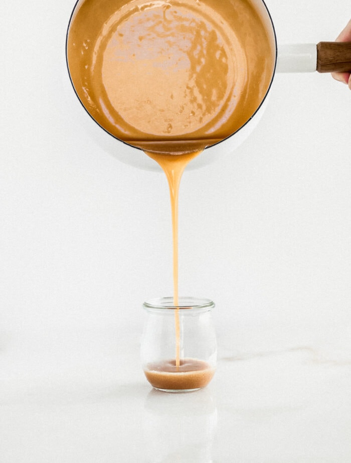 miso caramel sauce being poured into a glass jar.