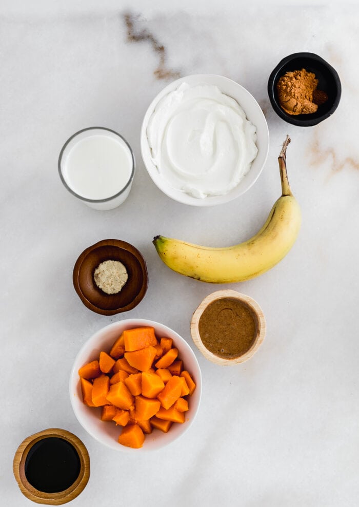 overhead view of ingredients for gingerbread sweet potato smoothie on a white background.
