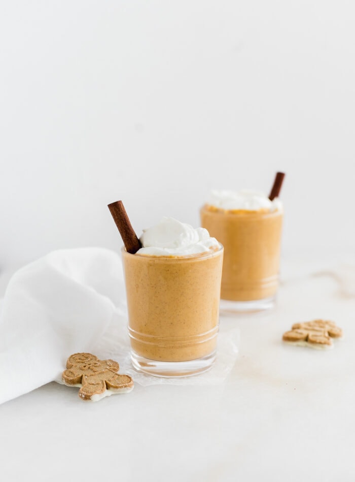two gingerbread sweet potato smoothies topped with whipped cream and cinnamon sticks.