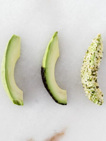 three slices of avocado, one plain, one with skin on half, and one rolled in hemp seeds.